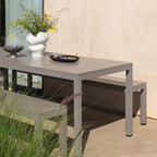 Taupe colour finish Rio Aluminium top outdoor table with a vase of flowers and a bowl on a patio