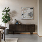 Modern living room with a walnut sideboard, decorative items, and abstract art.