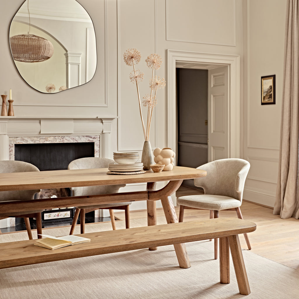 Dining room with wooden table, chairs, and bench in a well-lit room.