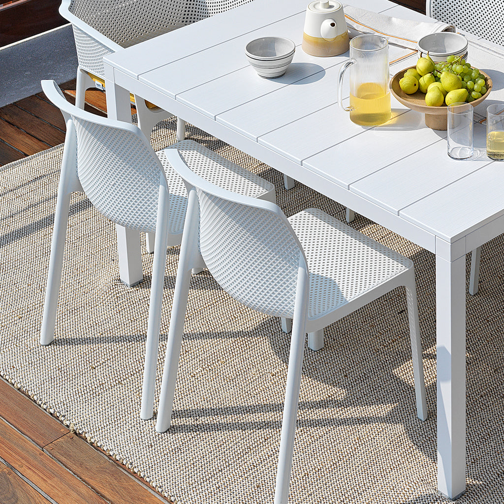 White outdoor table with Bit chairs by Nardi Outdoor on a wooden patio