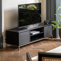 A black mango wood media unit with a gold-finish metal base, featuring a television on top and storage.