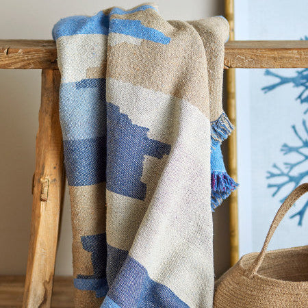 Soft blue throw blanket draped over a sofa in a modern living room.