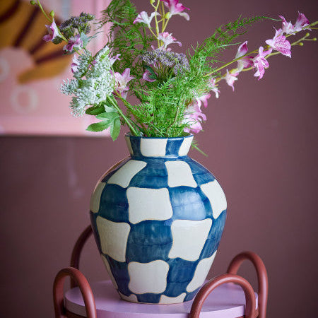 Blue and white checkered vase with flowers, creating a room set