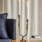 Decorative candle holder with two lit candles on a table.
