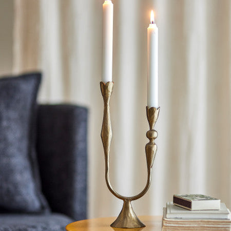 Decorative candle holder with two lit candles on a table.