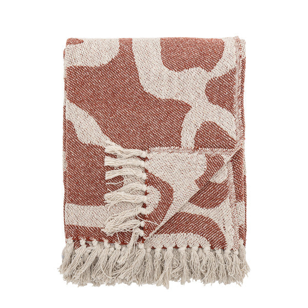 Red and white patterned throw blanket with fringes on a white background