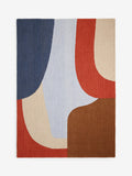 An abstract area rug with a modern geometric pattern of curved and angular blocks in navy blue, light blue, rust red, beige, and brown, shown flat against a plain white background.
