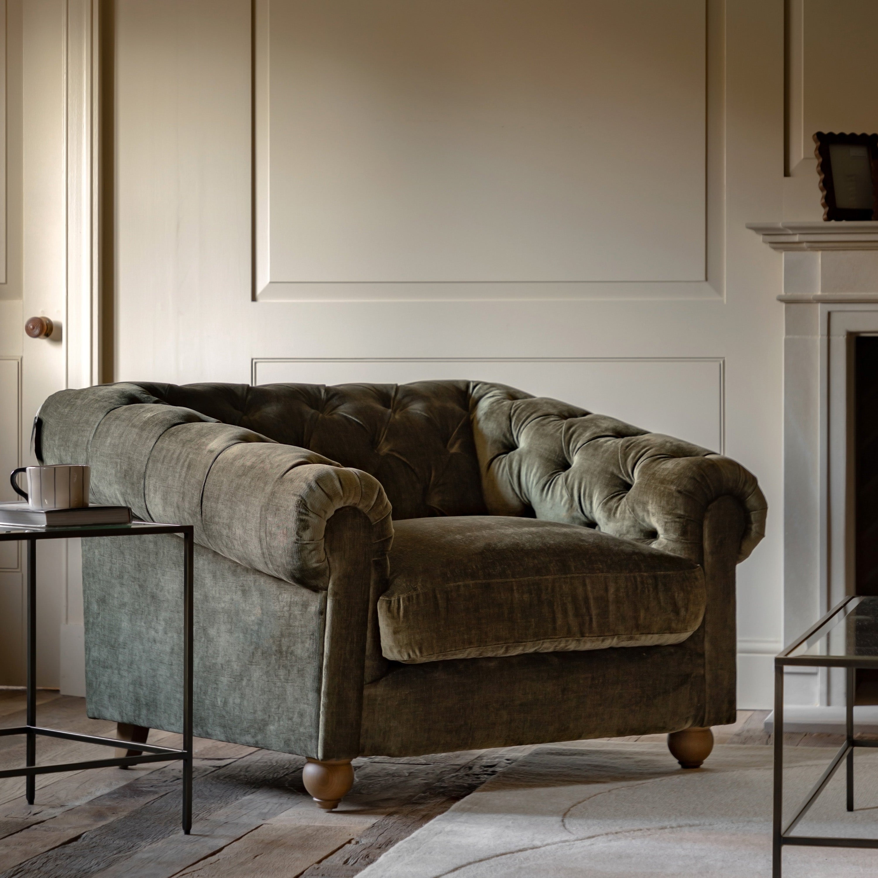 Green velvet sofa in a living room setting with a fireplace and coffee table.