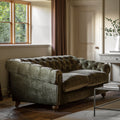 Green velvet sofa in a room with a window and side table.