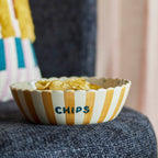Striped bowl labelled Chips with snacks on a textured surface