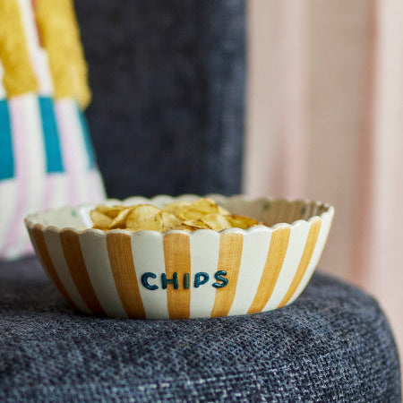 Striped bowl labelled Chips with snacks on a textured surface