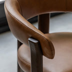 Close-up of a brown leather chair with armrests.
