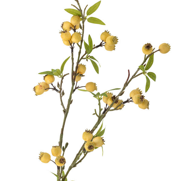 Close up of artificial plant branch with yellow flowers and green leaves on a white background