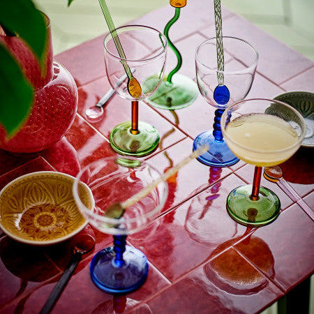 Colourful glasses with unique glass designs on a pink tiled table creating a room set
