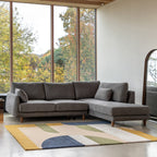 Gray Eva sectional sofa right hand facing in a room with large windows and a colorful rug.