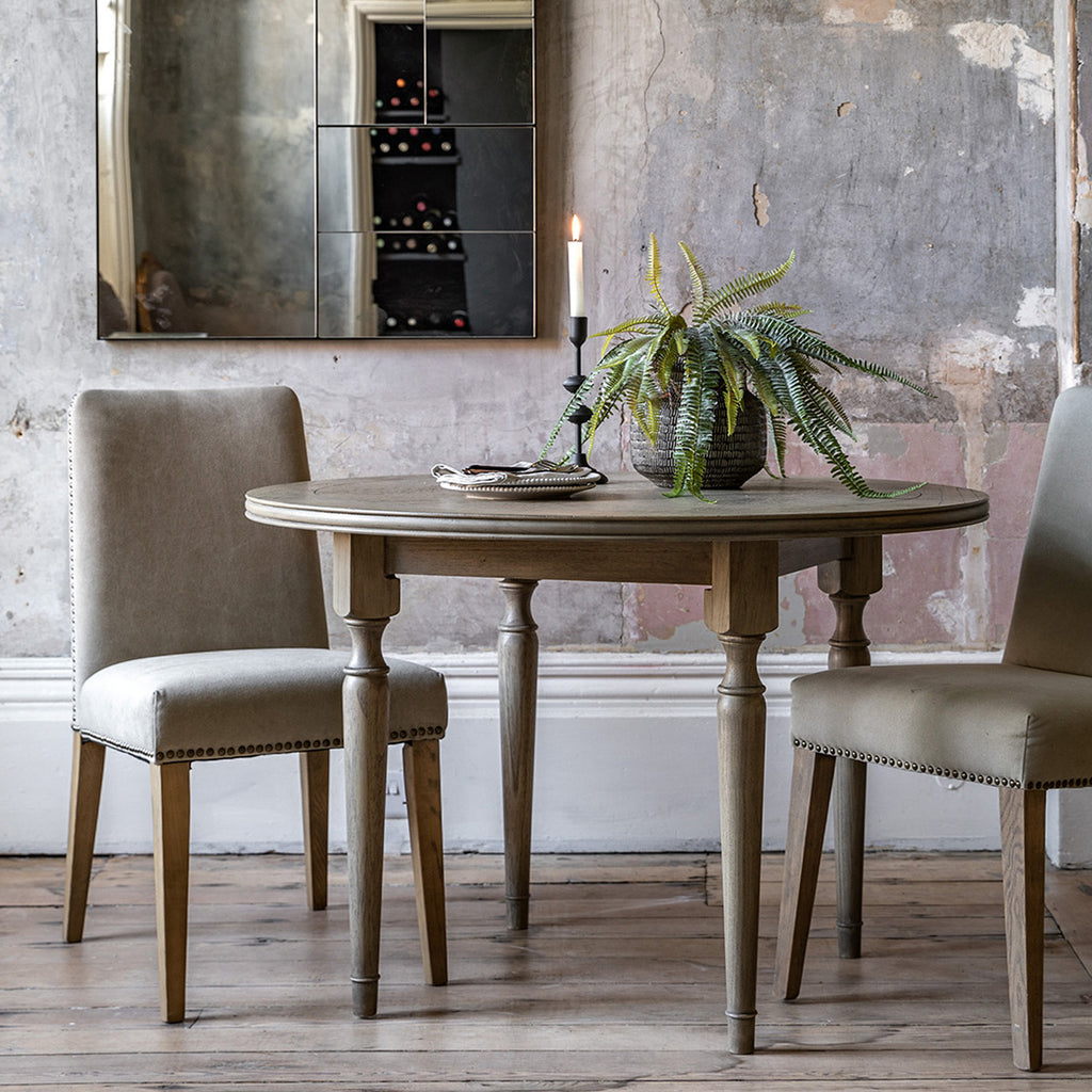 Faringdon Round Dining Table in a styled dining room setting with chairs, demonstrating its proportions and how it fits in a complete dining arrangement