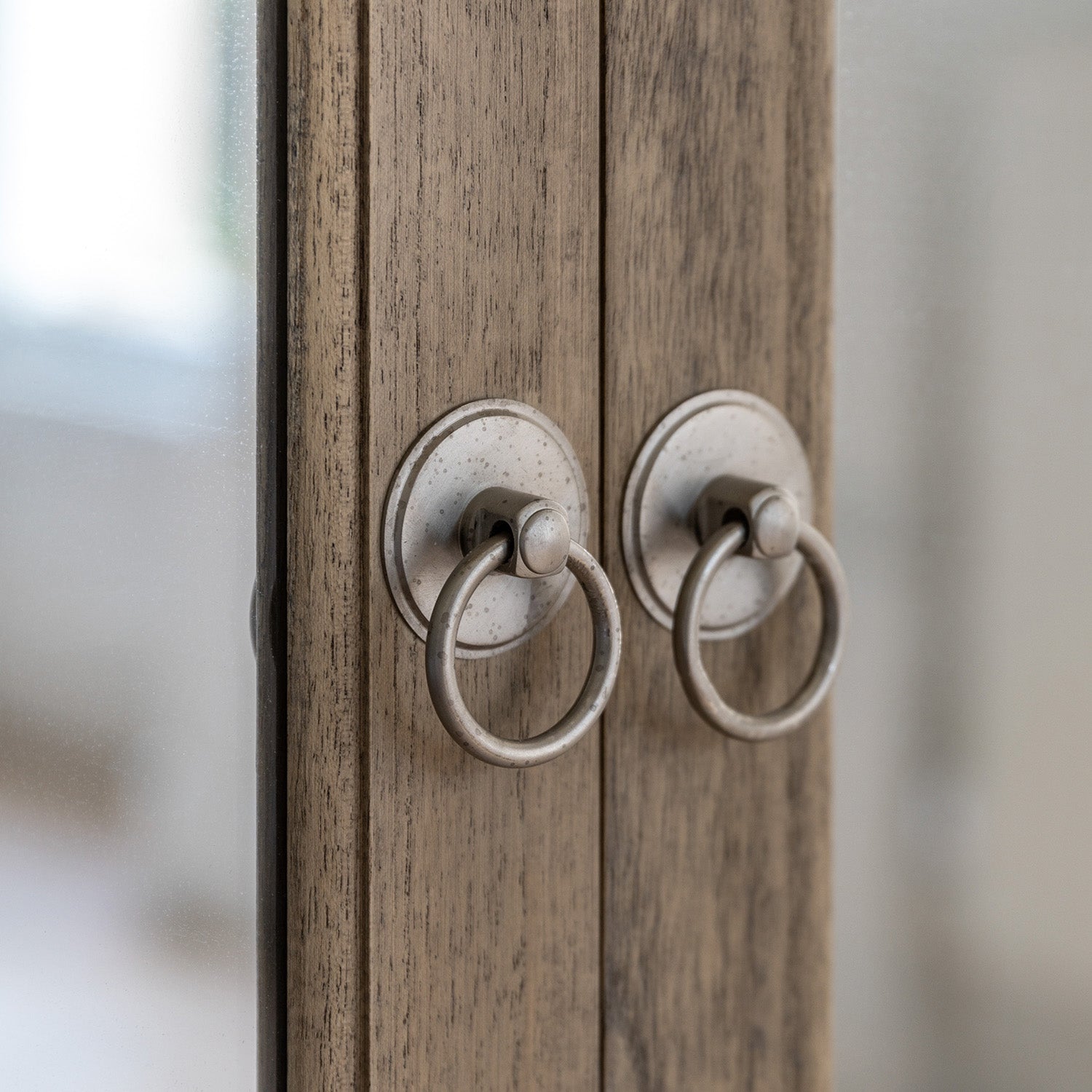 Detail view of Faringdon Wardrobe's door hardware, showing the brass handles and hinges that complement the natural wood finish