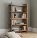 Wooden bookshelf with books and a cactus against a gray wall.