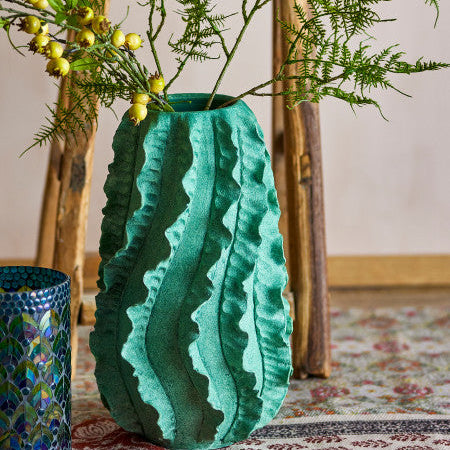 Turquoise textured vase with greenery on a wooden stool