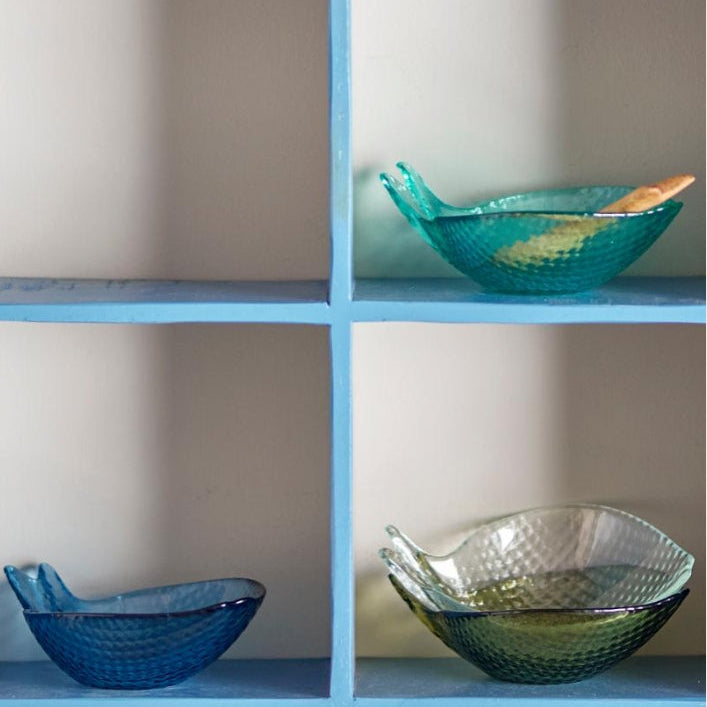 Three glass bowls on a blue shelf against a neutral wall