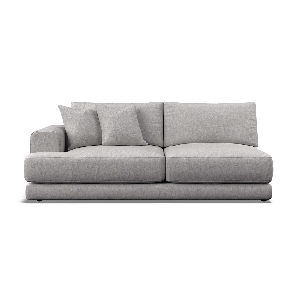 A modern low-profile sofa in light gray textured fabric, featuring two matching throw pillows, shown against a plain white background.