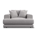A modern low-profile armchair in light gray textured fabric, featuring two matching throw pillows, shown against a plain white background.