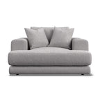 A modern low-profile armchair in light gray textured fabric, featuring two matching throw pillows, shown against a plain white background.