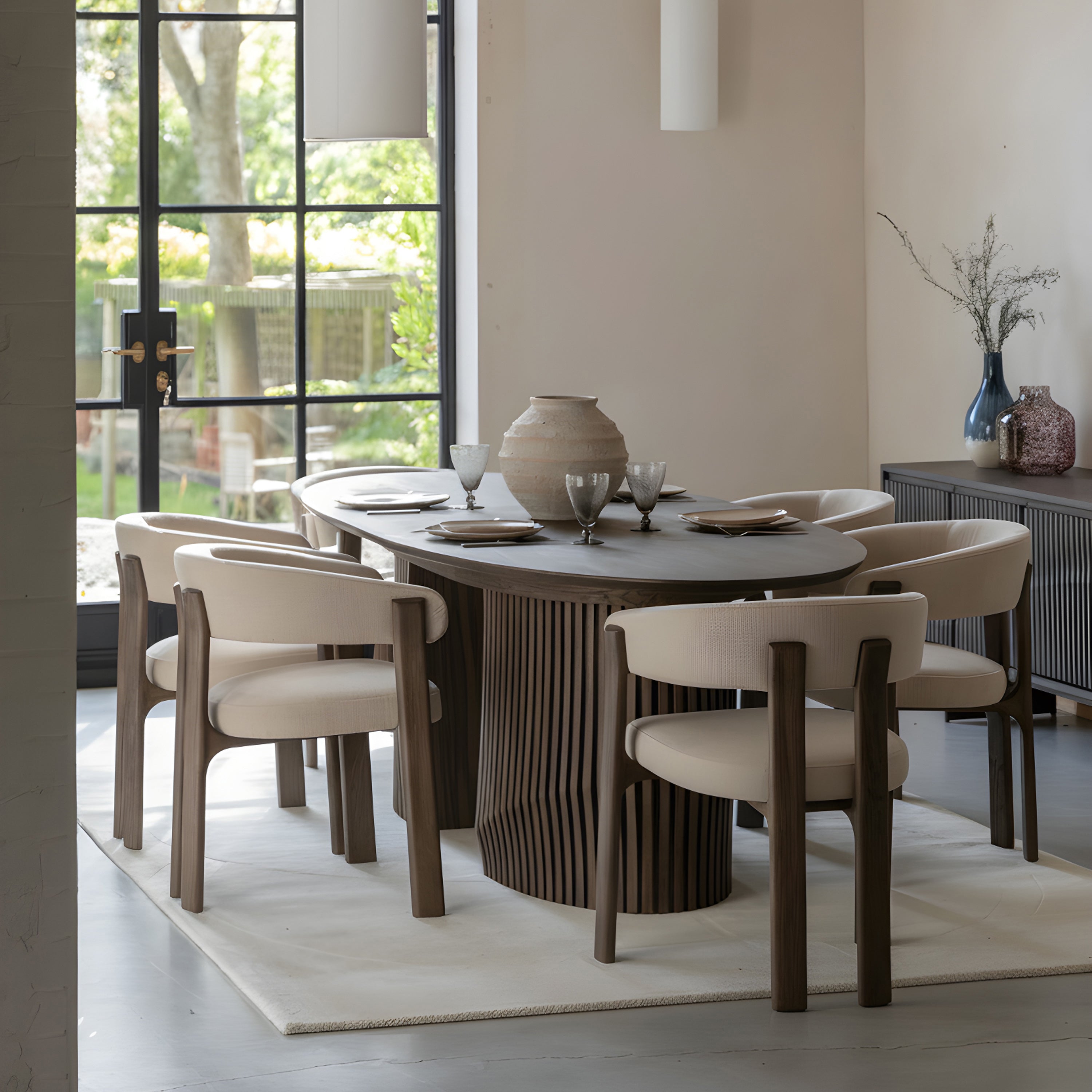Dining room with a round Walnut table and chairs near a large window.