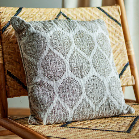 Decorative pillow with a geometric pattern on a wicker chair.