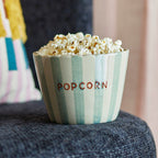 Striped bowl filled with popcorn on a blue cushion