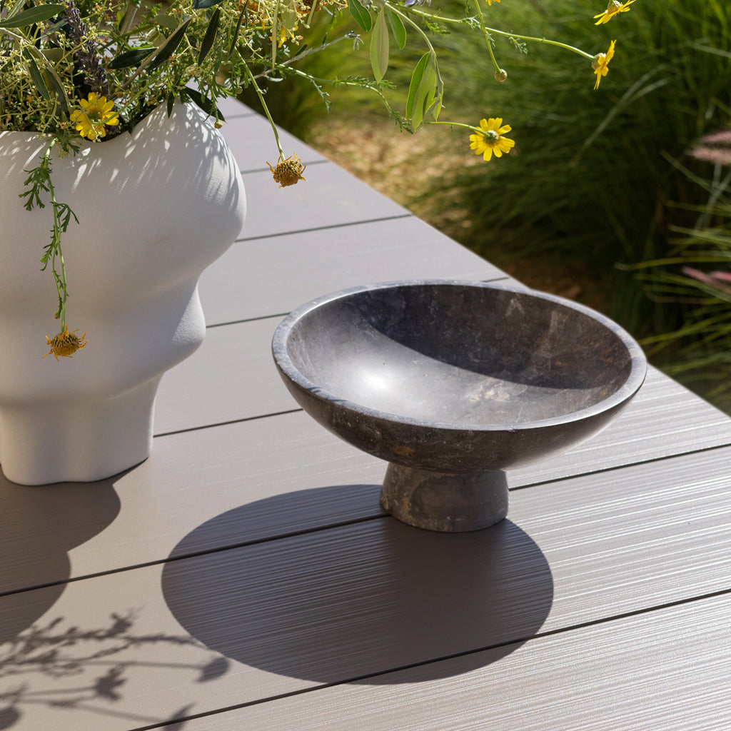 Decorative stone bowl on a Rio dining table by Nardi Outdoor with a potted plant in the background