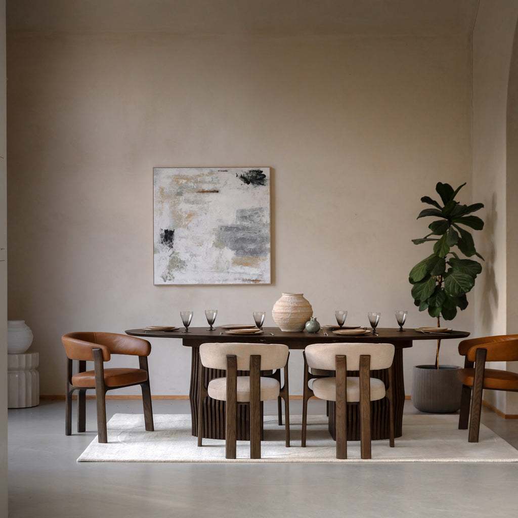 Dining room with Walnut table and chairs, abstract painting on the wall, and a plant.