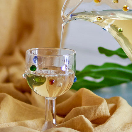 White wine being poured into the dotty glass with a blurred background
