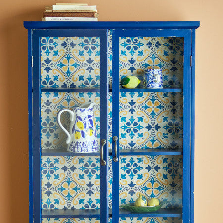 Blue cabinet with patterned doors against a beige wall