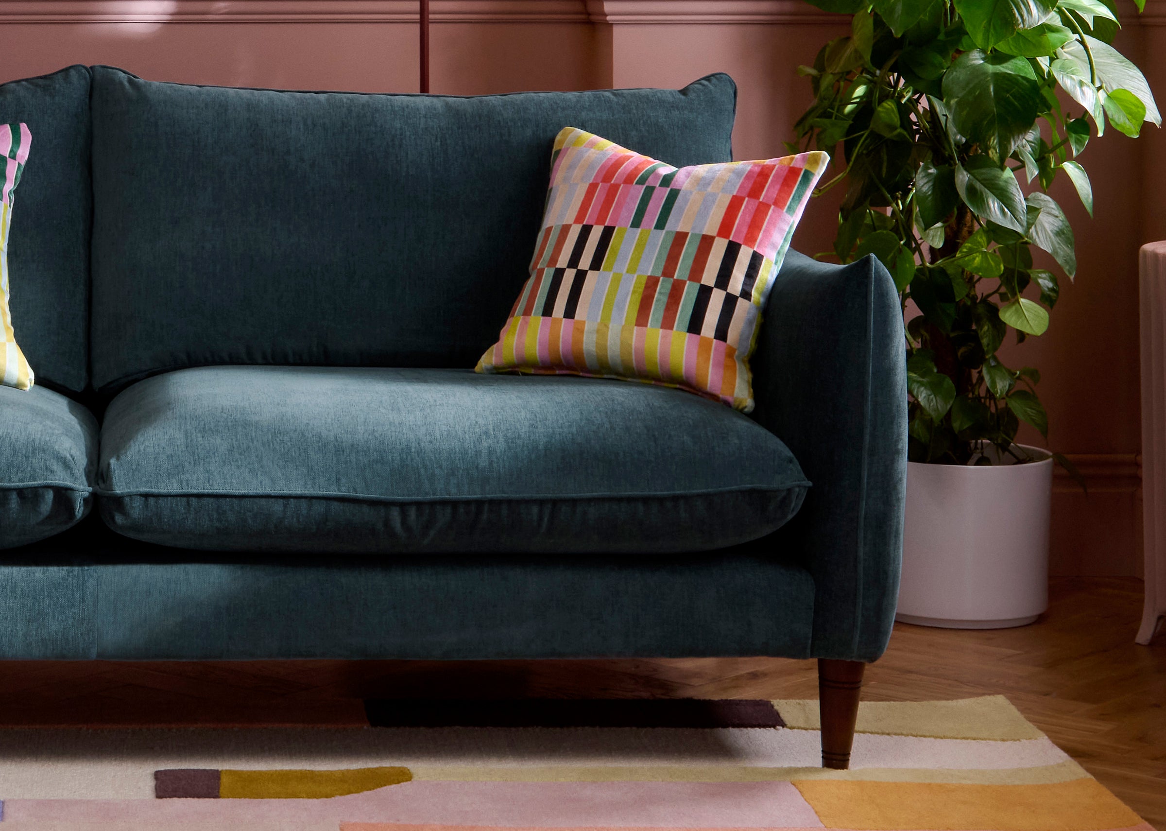 Kenmare Teal sofa with colourful pillow in a living room setting