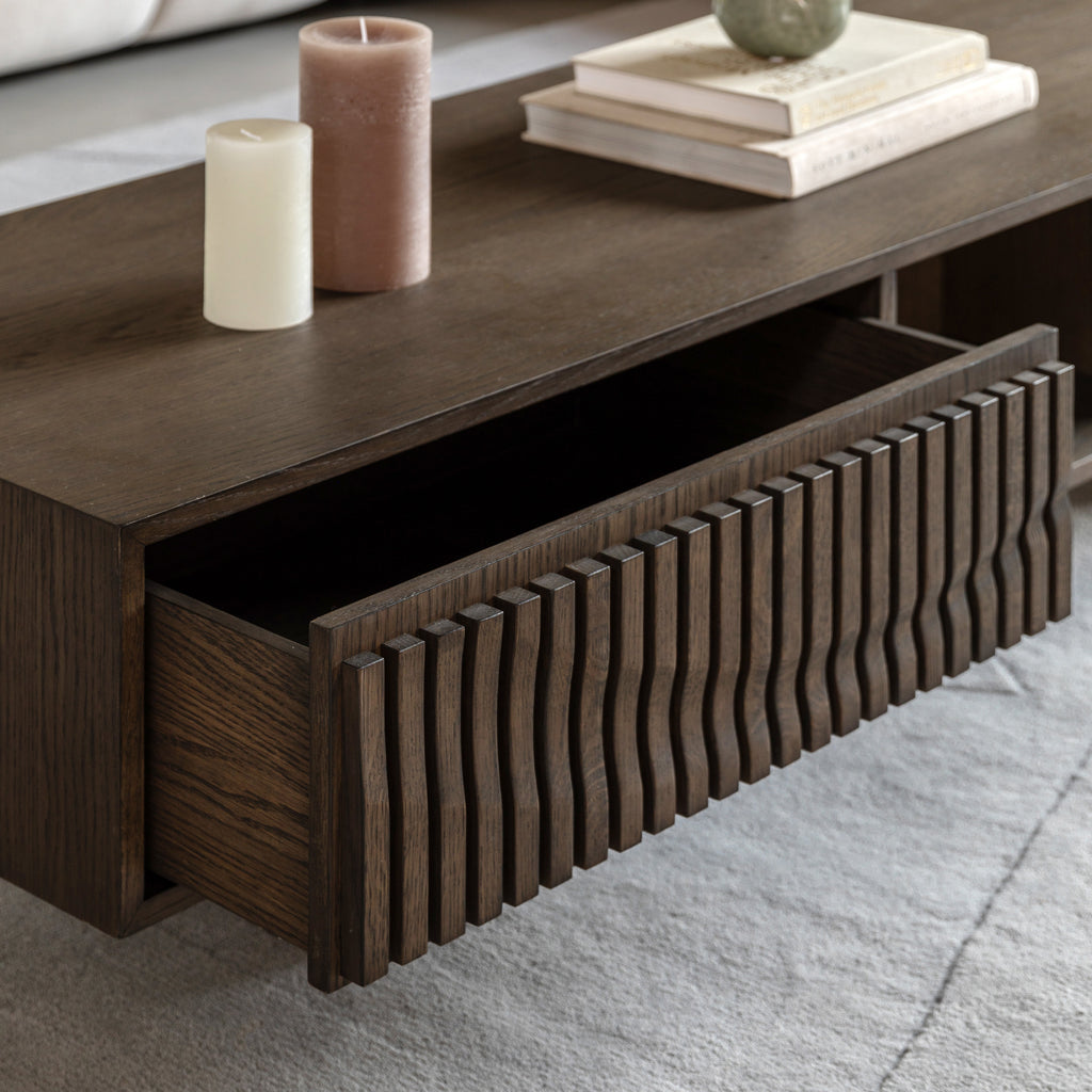 Walnut coffee table with a drawer, candles, and books on top.