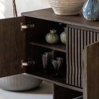 Walnut cabinet with open door revealing interior shelves with decorative items.