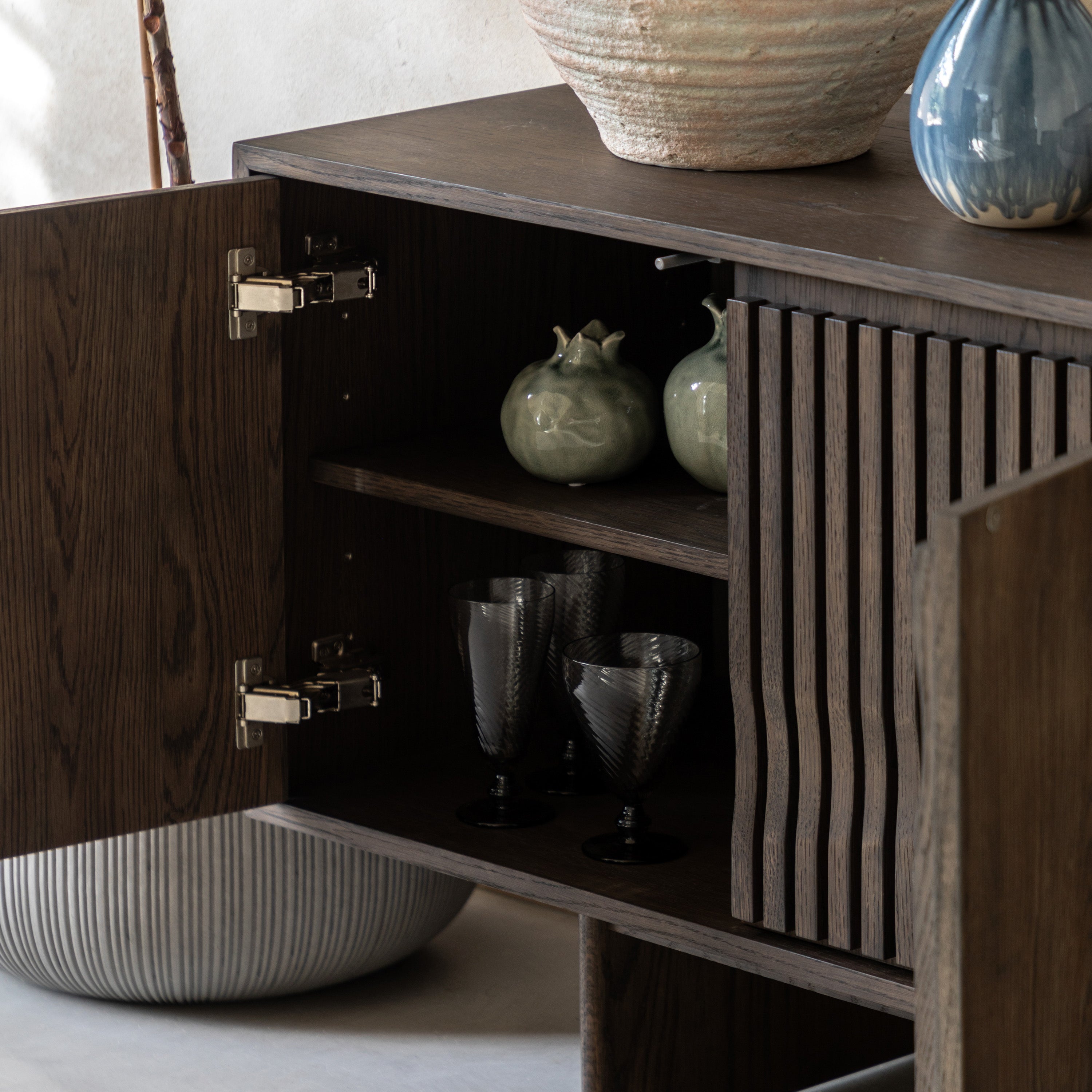 Walnut cabinet with open door revealing interior shelves with decorative items.
